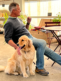 Owner Gordon drinking with Winnie the Farm Dog sitting by his side.